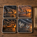 Four square ceramic coasters with rounded corners featuring ducks and geese landing at sunset, arranged on a wooden surface next to a book.