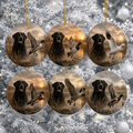 Six round Christmas ceramic ornaments hanging from gold strings against a snowy Christmas tree background. Each ornament features a printed scene of a black Labrador retriever beside ducks and geese at sunset over marshland.